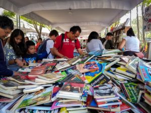 Asistentes a la Feria del Libro Para Leer en Libertad en la Ciudad de México buscan entre un montón de libros de venta. La feria se llevó a cabo del 8 al 17 de diciembre de 2017. Foto: Eduardo Barraza | Barriozona Magazine © 2017
