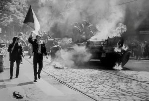 Imagen captada durante la invasión soviética de Checoslovaquia en 1968, en la que se observa a jóvenes manifestantes checoslovacos llevando su bandera nacional junto a un tanque en llamas en la ciudad de Praga. Foto: Dominio Público