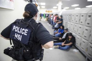 Un agente de ICE observa a varios trabajadores detenidos dentro de una las plantas procesadoras de alimentos durante una de las redadas de inmigración en Mississippi. Foto: ICE