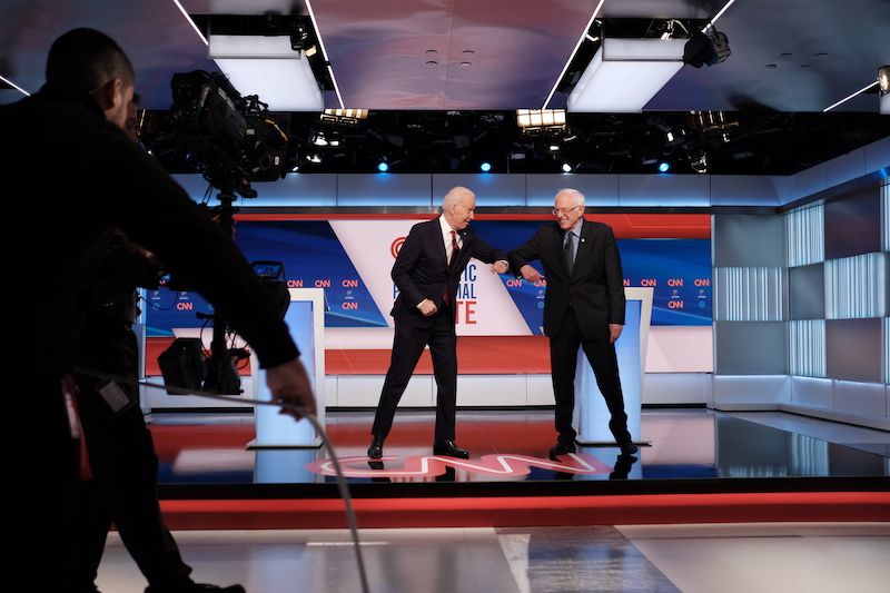 El ex vicepresidente Joe Biden y el senador de Vermont Bernie Sanders se saludan con los antebrazos al inicio del debate demócrata en Washington, el domingo 15 de marzo. Foto: CNN