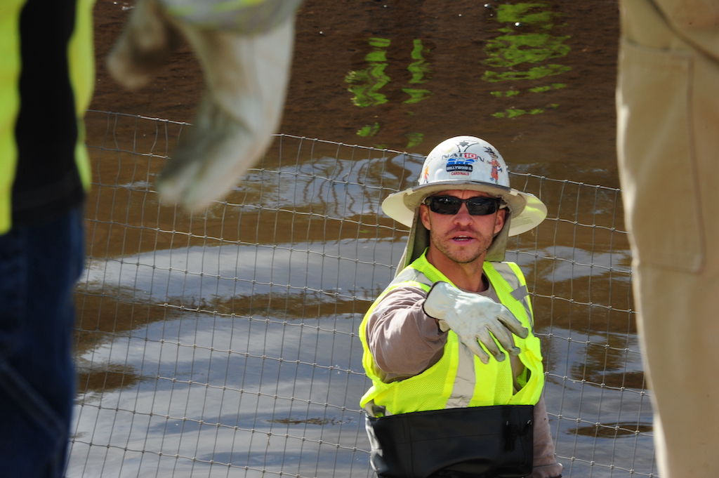 Kyle Quiroz, Especialista en Aplicación de Productos Químicos de SRP, dirige a los miembros de la cuadrilla durante el traslado y reubicación de los peces amur blanco en un canal de Mesa, Arizona, cerca de McKellips Road y Stapley Drive. “Retiramos los peces para hacer reparaciones. También son como nuestros trabajadores, limpiando el canal por nosotros”, explicó Quiroz. Foto: Eduardo Barraza | Barriozona Magazine © 2024